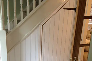 Tongue and groove panelling and a cupboard door under a staircase